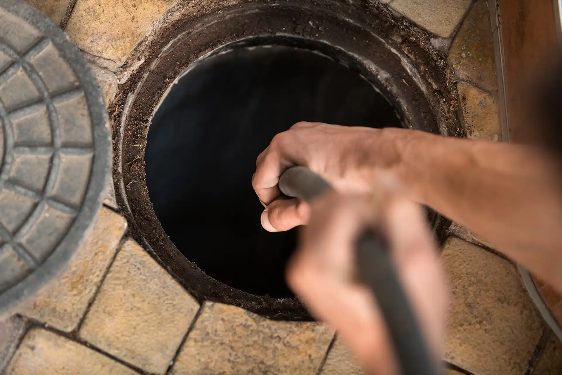 Technician performing hydro jet cleaning on underground pipe system for HVAC maintenance.